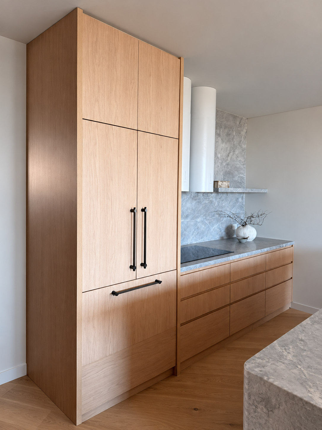 Oak kitchen cabinetry with stone benchtops and black handles